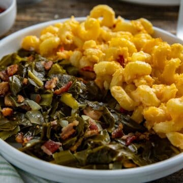 Cooked collard greens on a white plate with mac and cheese.