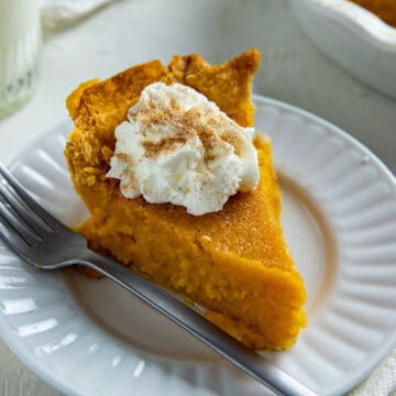 A slice of pie with dollop of whipped cream and sprinkling of cinnamon-sugar mixture.