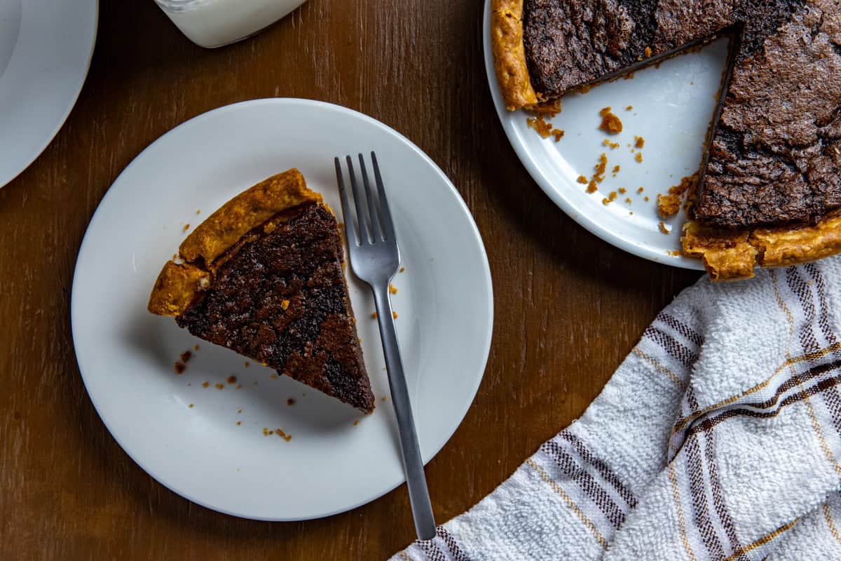 A slice of baked pie on a white plate with a fork.