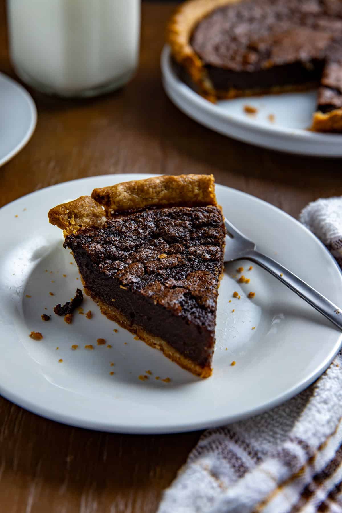 A slice of baked pie on a white plate with a fork.
