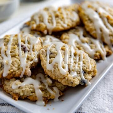 Baked and frosted cookies piled on a white rectangular platter.