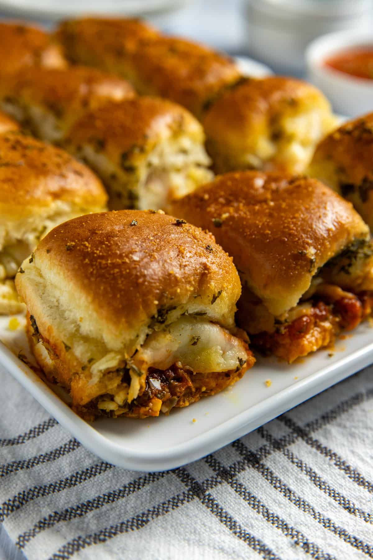 Baked meatball sliders on white serving platter.