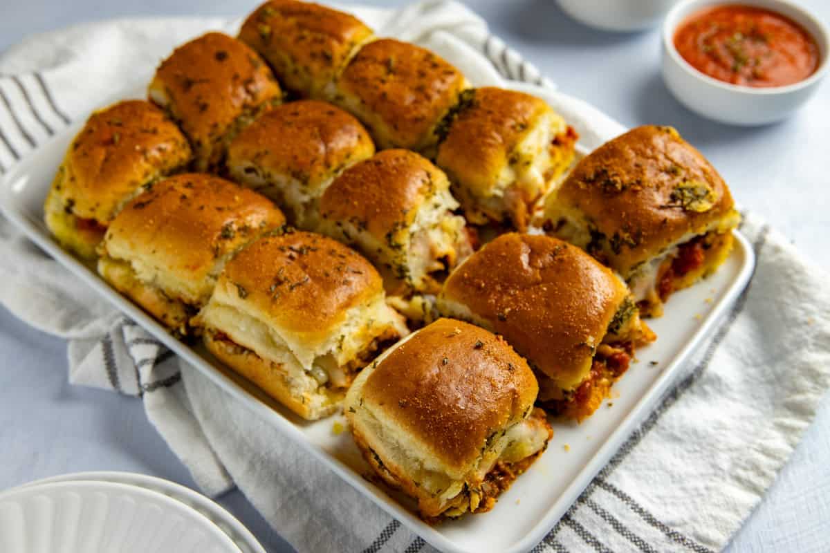 Baked meatball sliders on white serving platter.