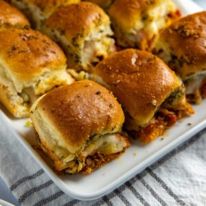 Baked meatball sliders on white serving platter.