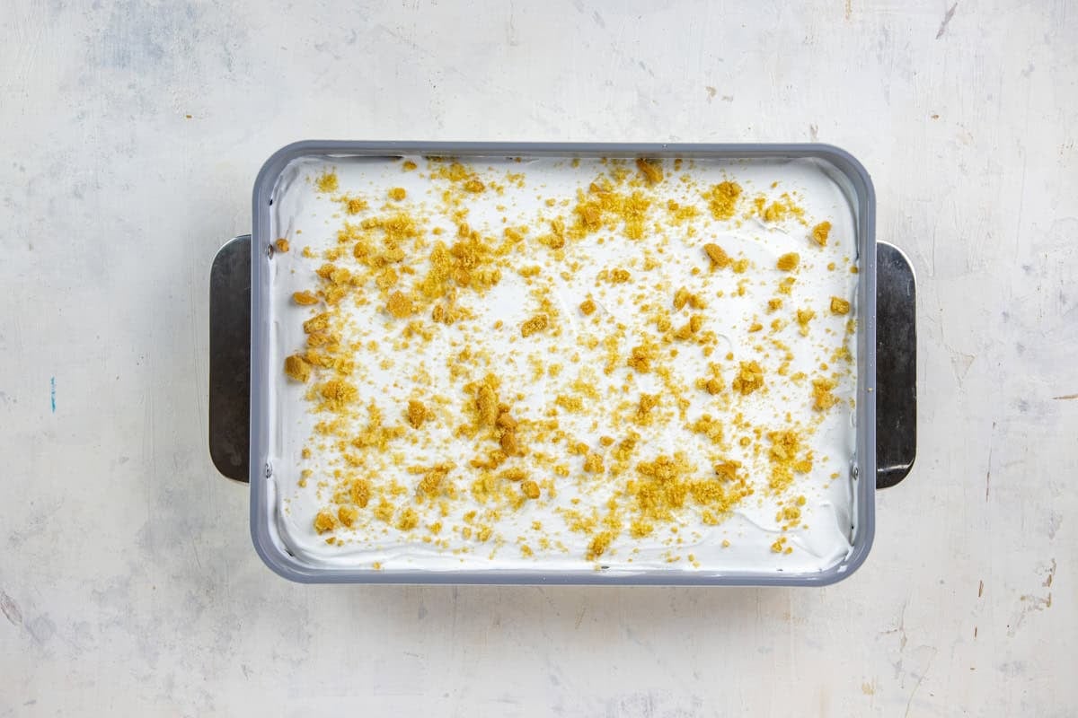 Crushed cookies sprinkled on top of the whipped topping in a 9x13-inch baking pan.