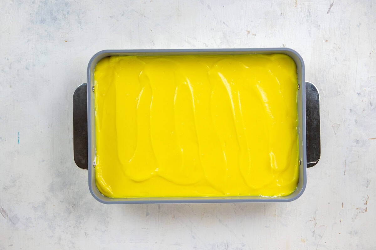 Lemon pudding spread on top of the cream cheese mixture in a 9x13-inch baking pan.