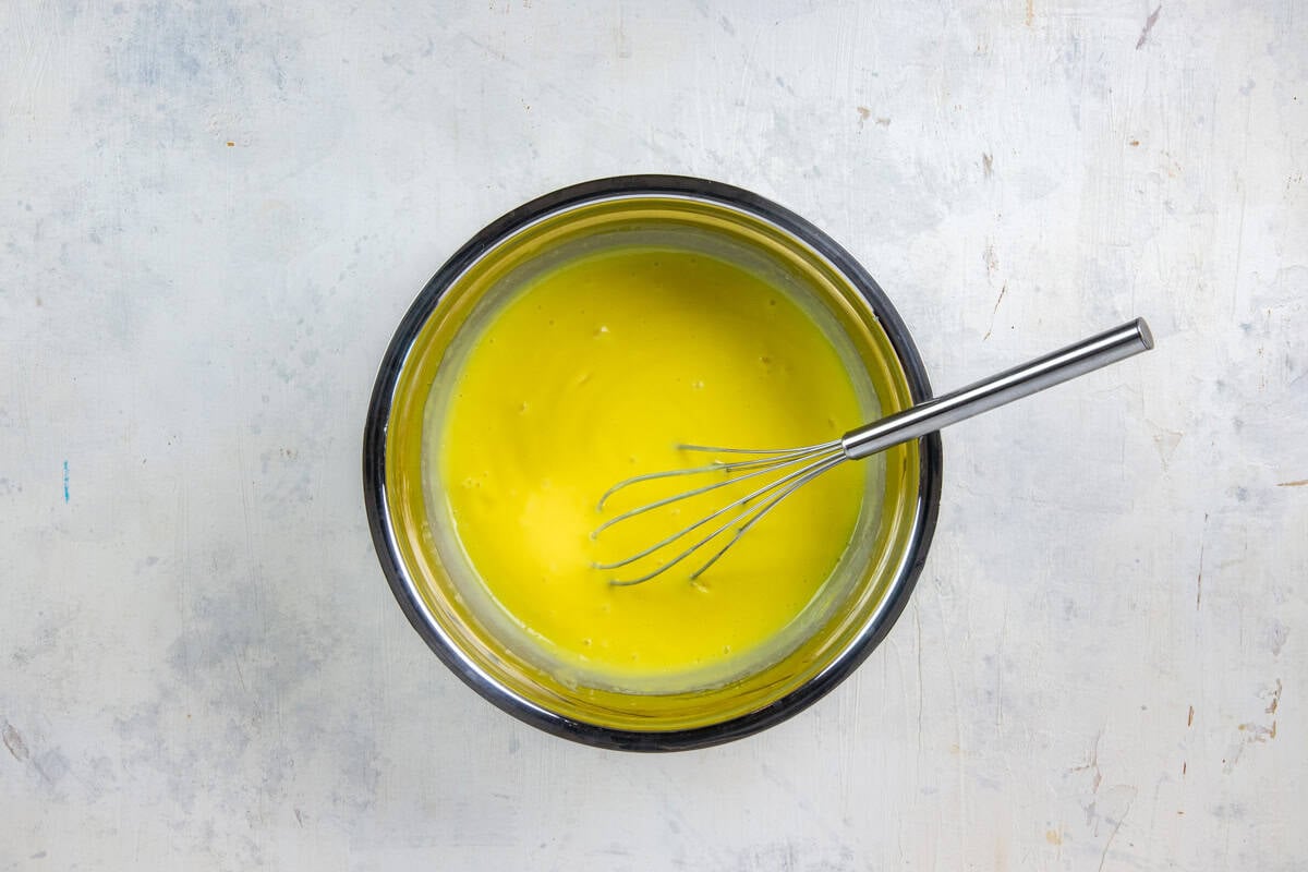 Stainless steel mixing bowl with instant lemon pudding mix and milk all mixed up.