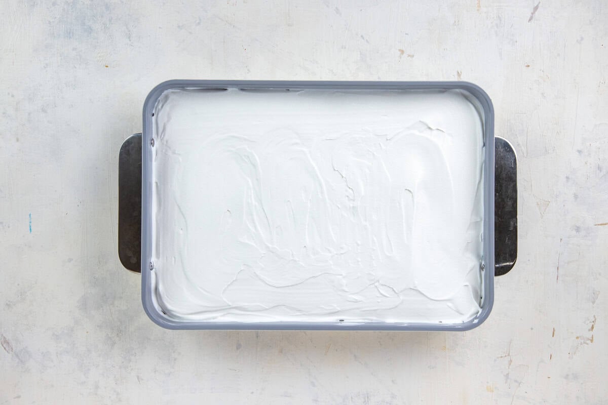 Whipped topping spread on top of the pudding layer in a 9x13-inch baking pan.