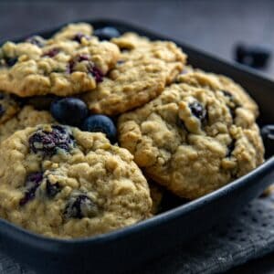 Baked cookies piled high in a large, black bowl.