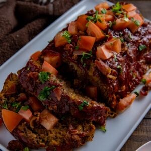 Baked and sliced meatloaf on a white serving platter.