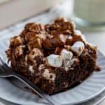 One square slice of Mississippi Mud Cake on a white plate with a fork.