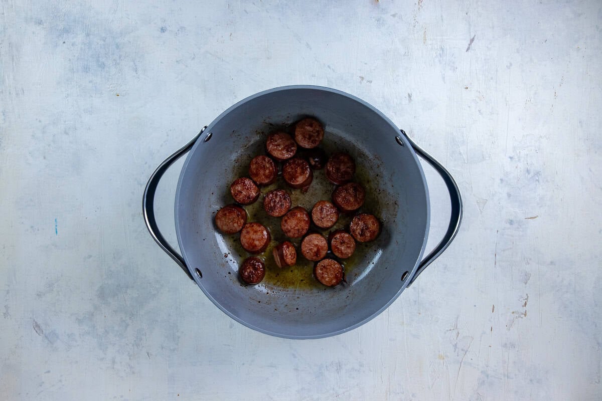 Cut up sausage browned in a pot.