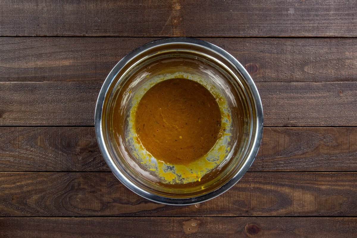 Eggs, onion powder, salt, pepper, ketchup, mustard, and Worcestershire sauce blended in a sterling silver mixing bowl.