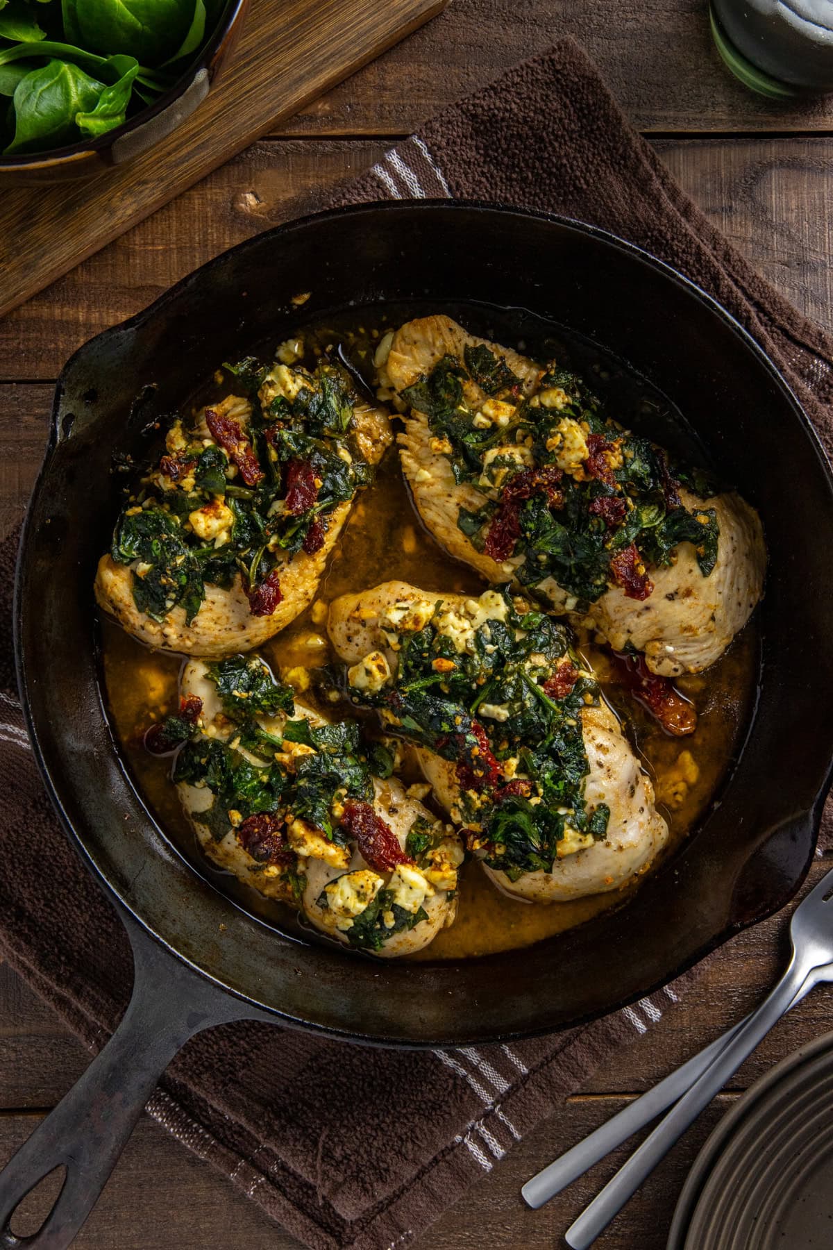 Baked chicken breasts with feta topping in a cast iron skillet.