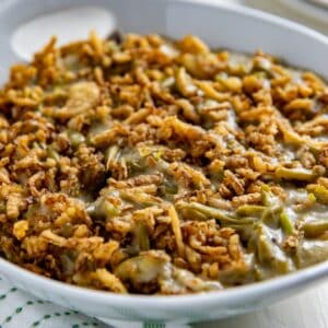 Cooked green bean casserole that's been placed in a white serving bowl.