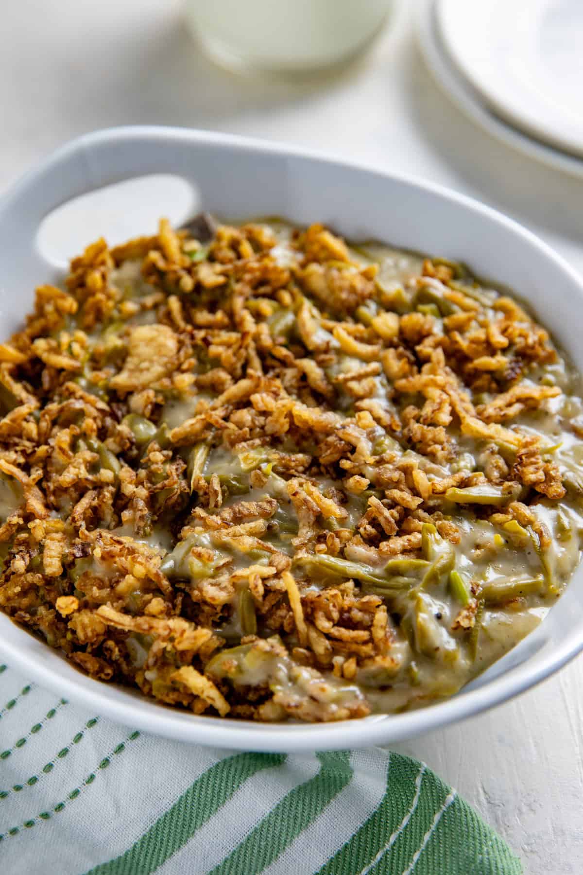 Cooked crockpot green bean casserole that's been transferred to a white serving bowl.