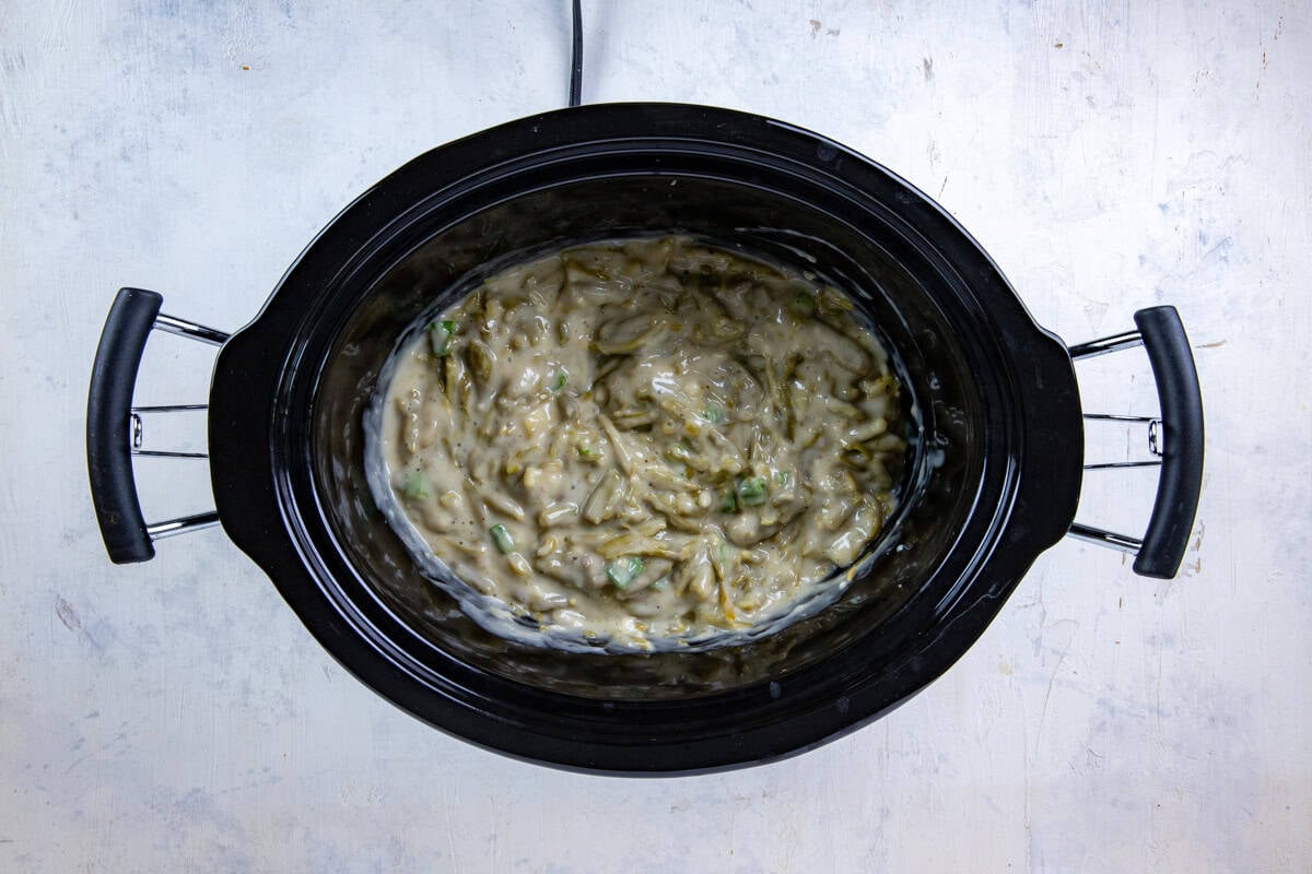 Soups, green onions, milk, soy sauce, garlic, and pepper added to the green beans then mixed together in the slow cooker.