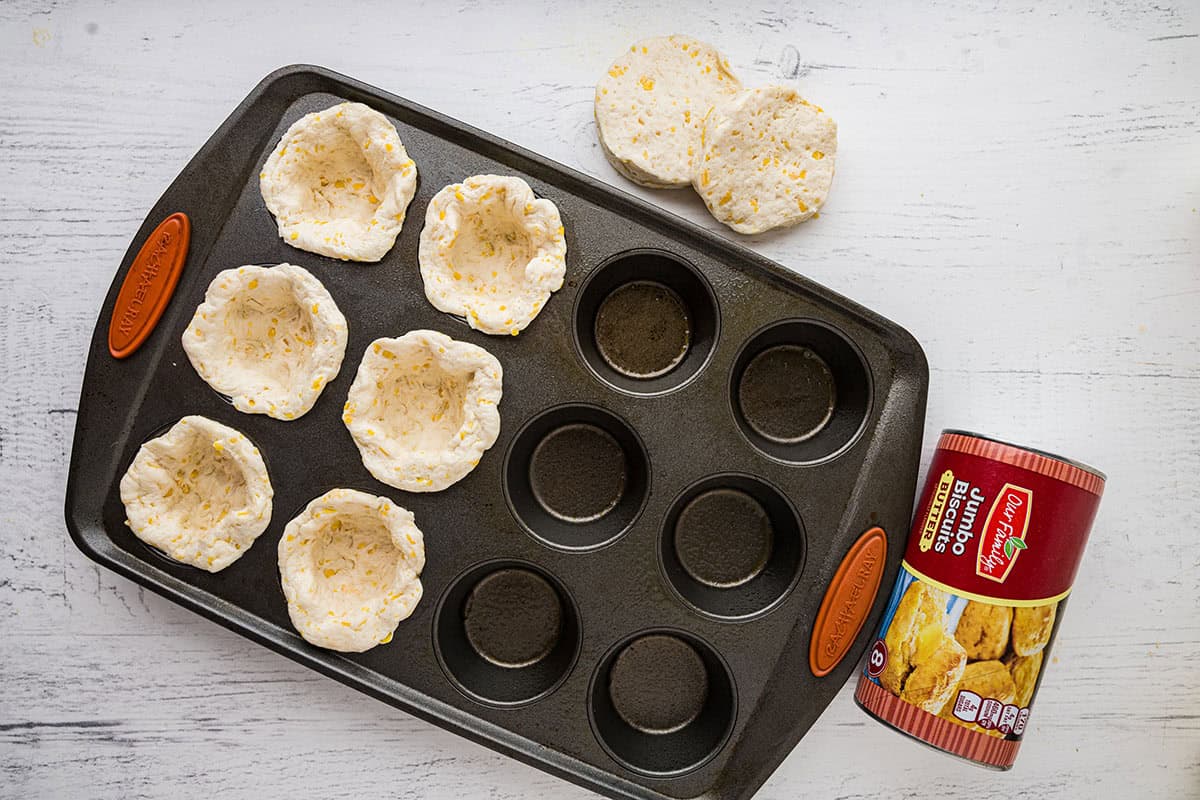 Biscuit dough pressed into a muffin pan.