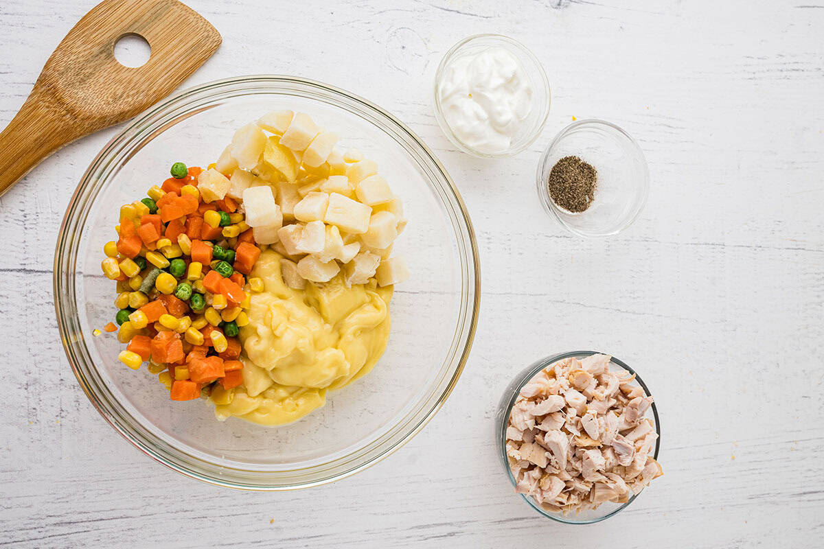 Diced chicken, cream of chicken soup, mixed vegetables, and sour cream mixed up in a bowl.
