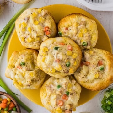 Overhead shot of 6 baked mini chicken pot pies arranged on a yellow plate.