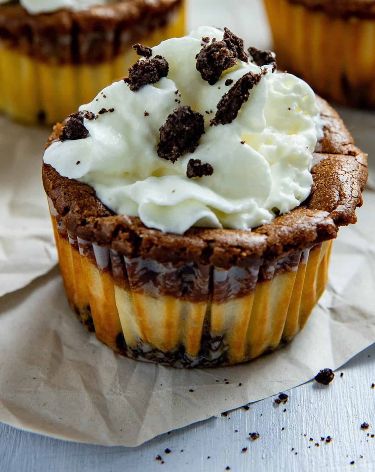 One baked Nutella Oreo Cheesecake Cup with whipped topping and some crushed Oreo crumbs.