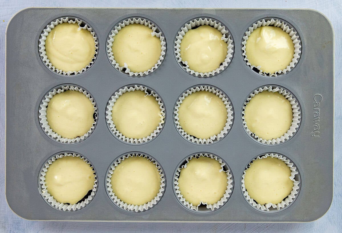 Vanilla cheesecake layer on top of Oreo crusts in the muffin pan.