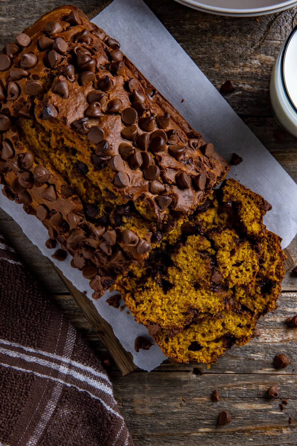 Overhead view of baked pumpkin bread with 2 slices stacked in front of the bread.