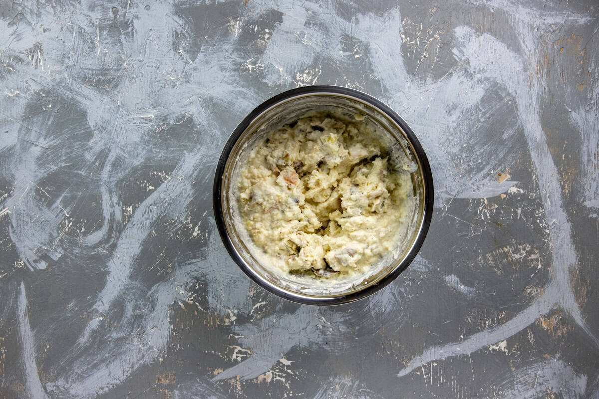 Roasted and mashed potatoes in a bowl mashed with butter, sour cream, salt, and pepper.