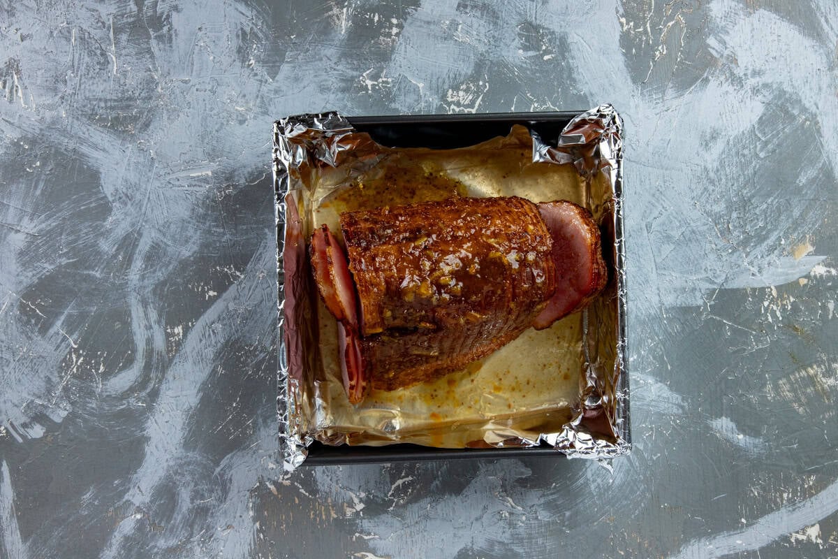 Glazed ham in a baking pan after the first bake.
