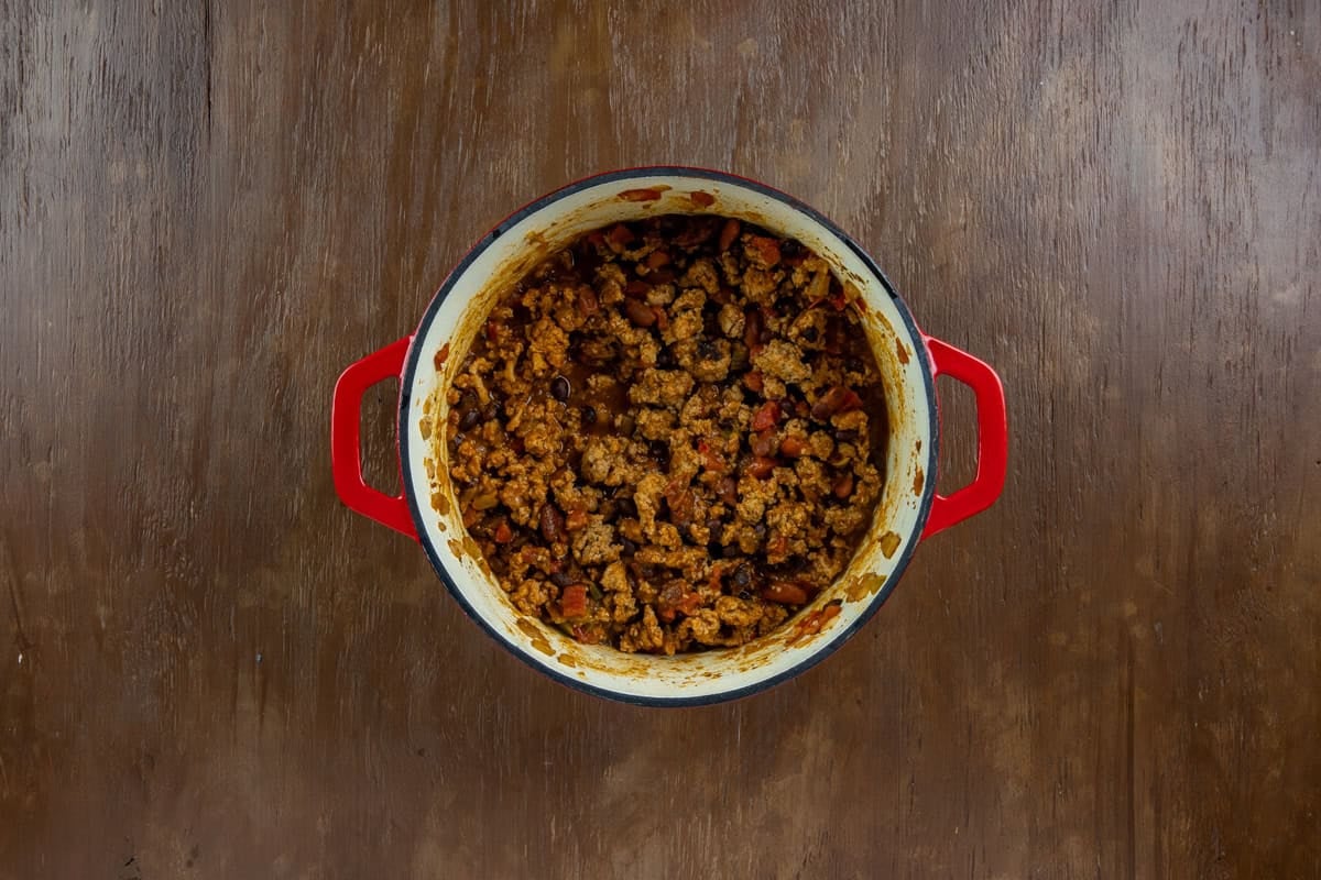 Cooked chicken chili in the red dutch oven.