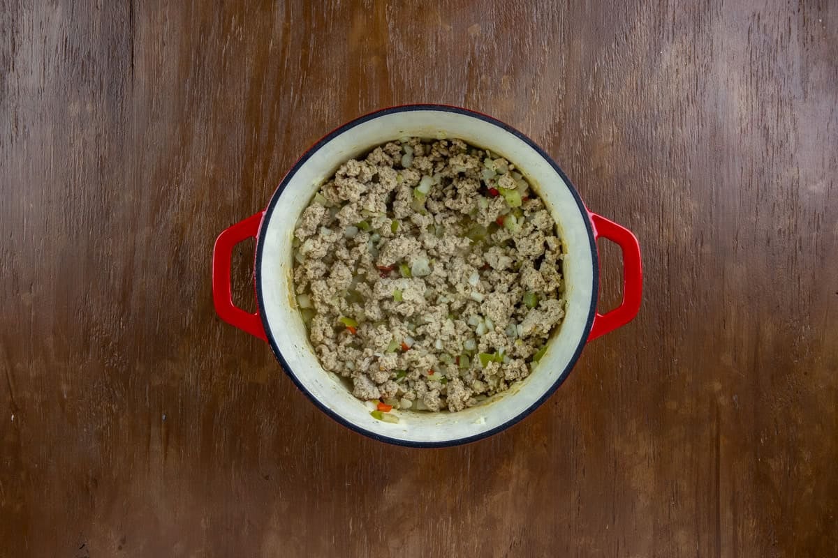 Chopped onion, belll pepper, and celery added to the cooked ground chicken in the dutch oven.