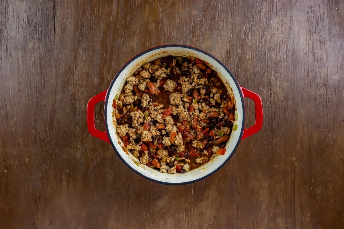 Kidney beans, black beans, tomatoes, tomato sauce, and all the seasonings added to the chili in the dutch oven.