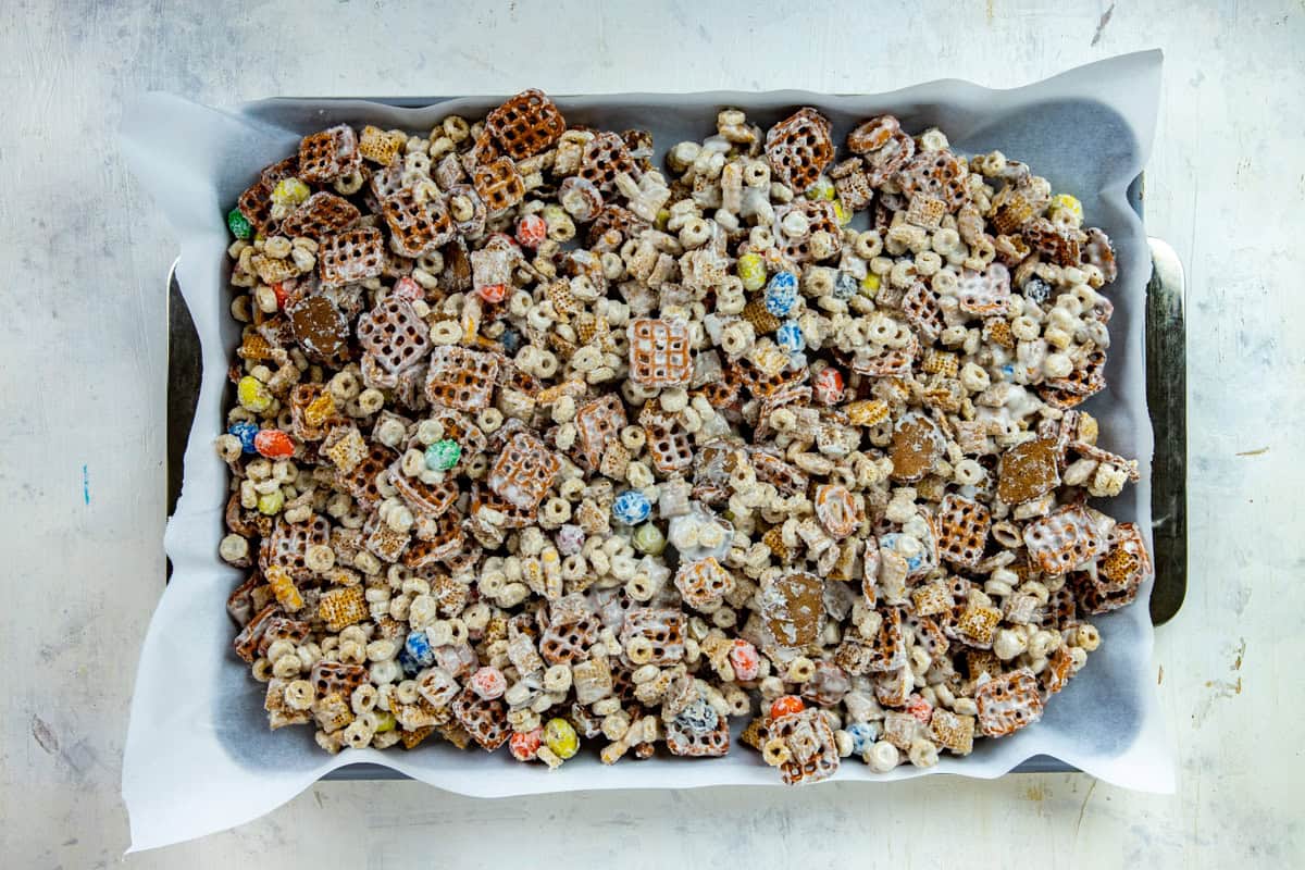 White chocolate snack mix on a large sheet pan lined with parchment paper.