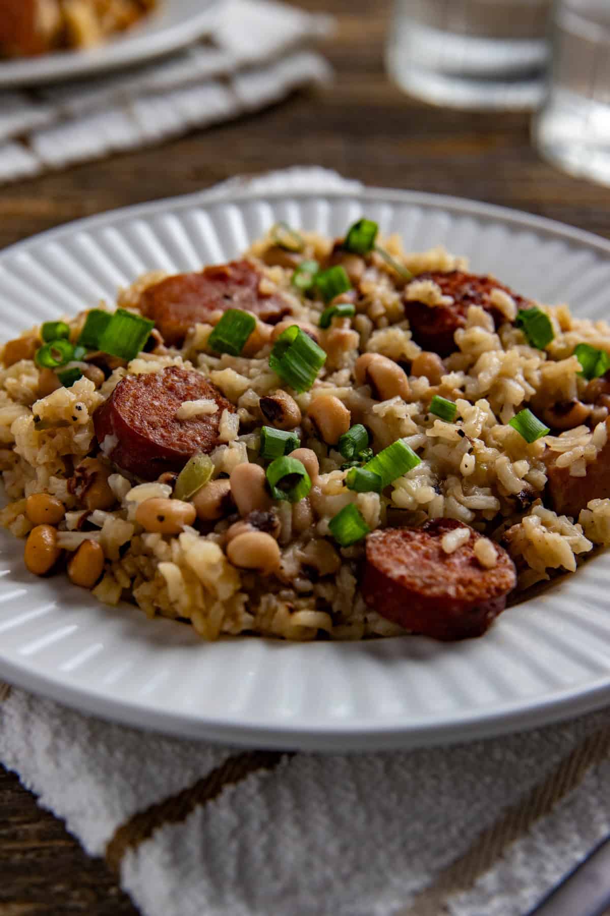 Cooked Hoppin John garnished with sliced green onions on a white plate.