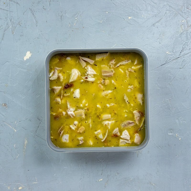 Water, bouillon, soup, and seasonings mixture poured over the chicken.