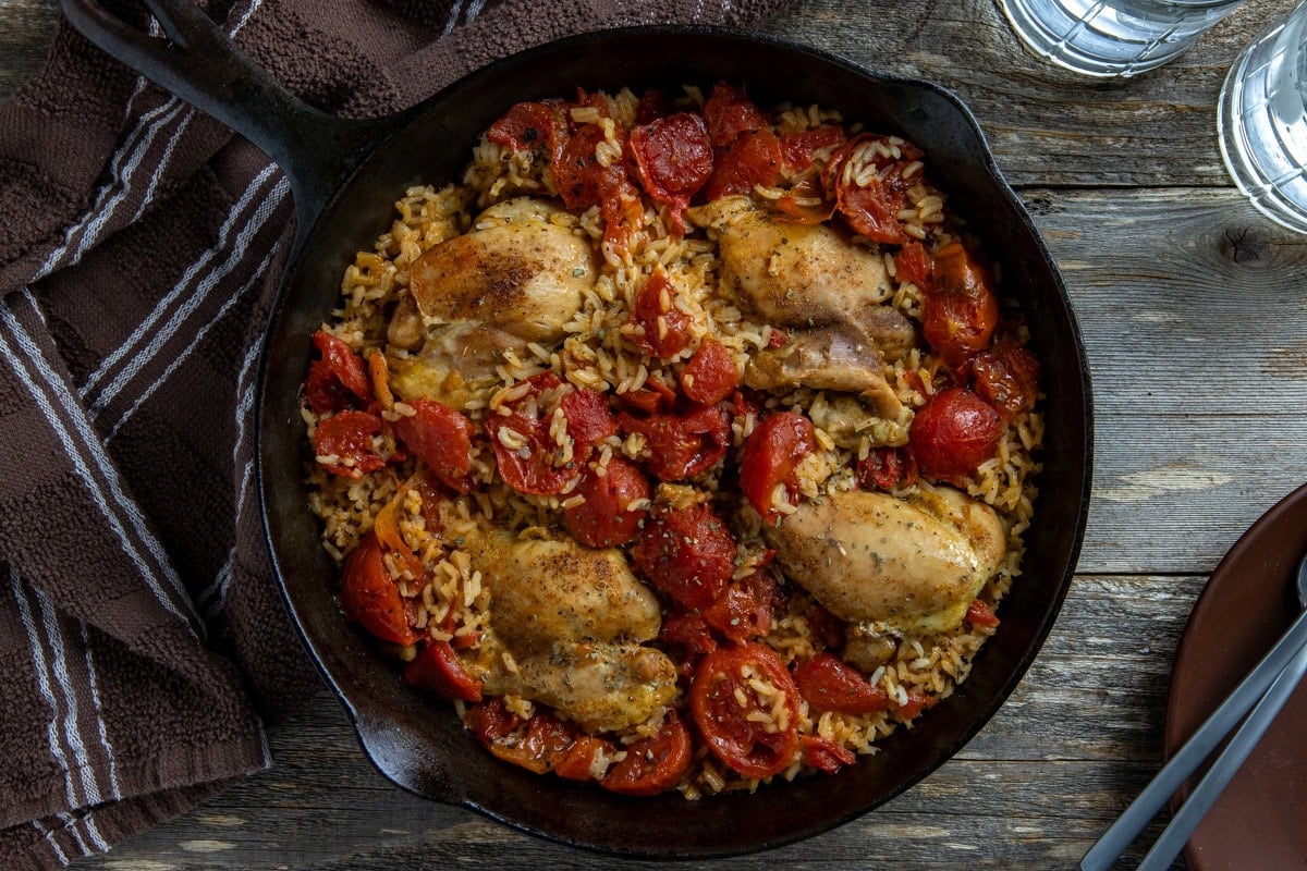 Cooked chicken and rice in a black cast iron skillet.