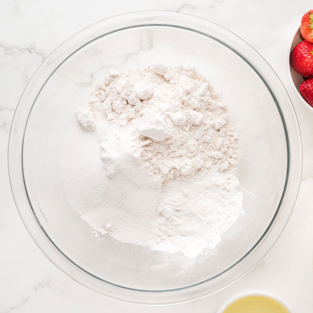 Flour, sugar, and baking powder in a glass mixing bowl.