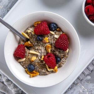 Cooked chia pudding topped with raspberries and nuts.