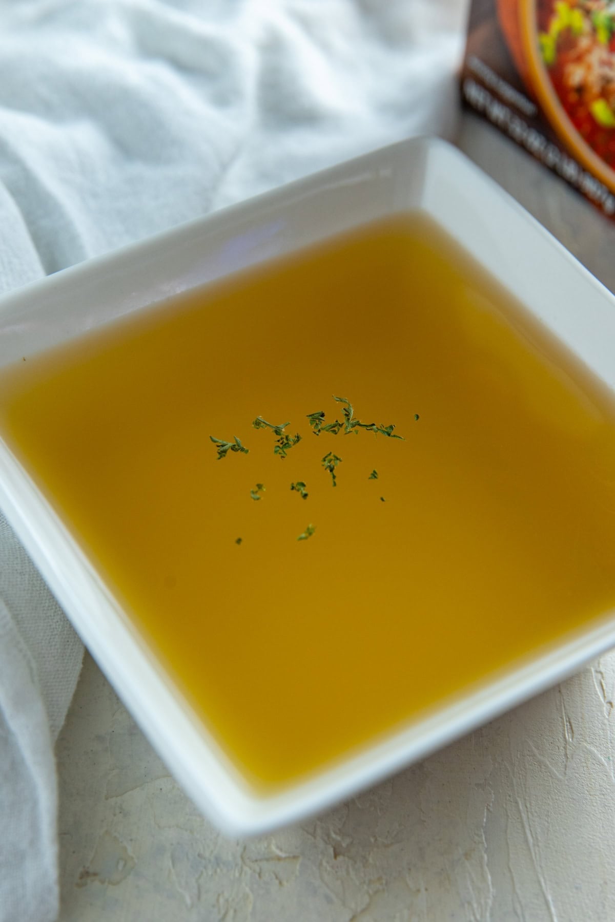 Chicken broth in a white square bowl.