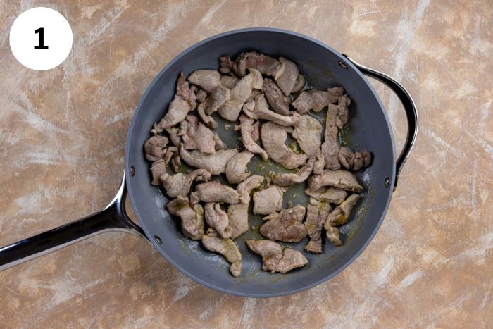 Sliced pork cooked in a large skillet.