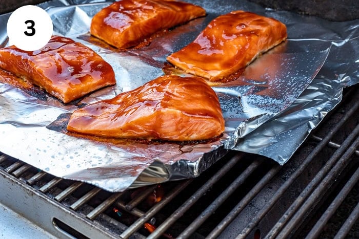 Four fillets brushed with BBQ sauce on foil on the grill.