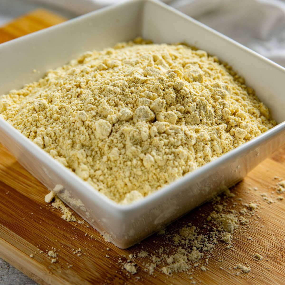 Chickpea flour in a square, white bowl.