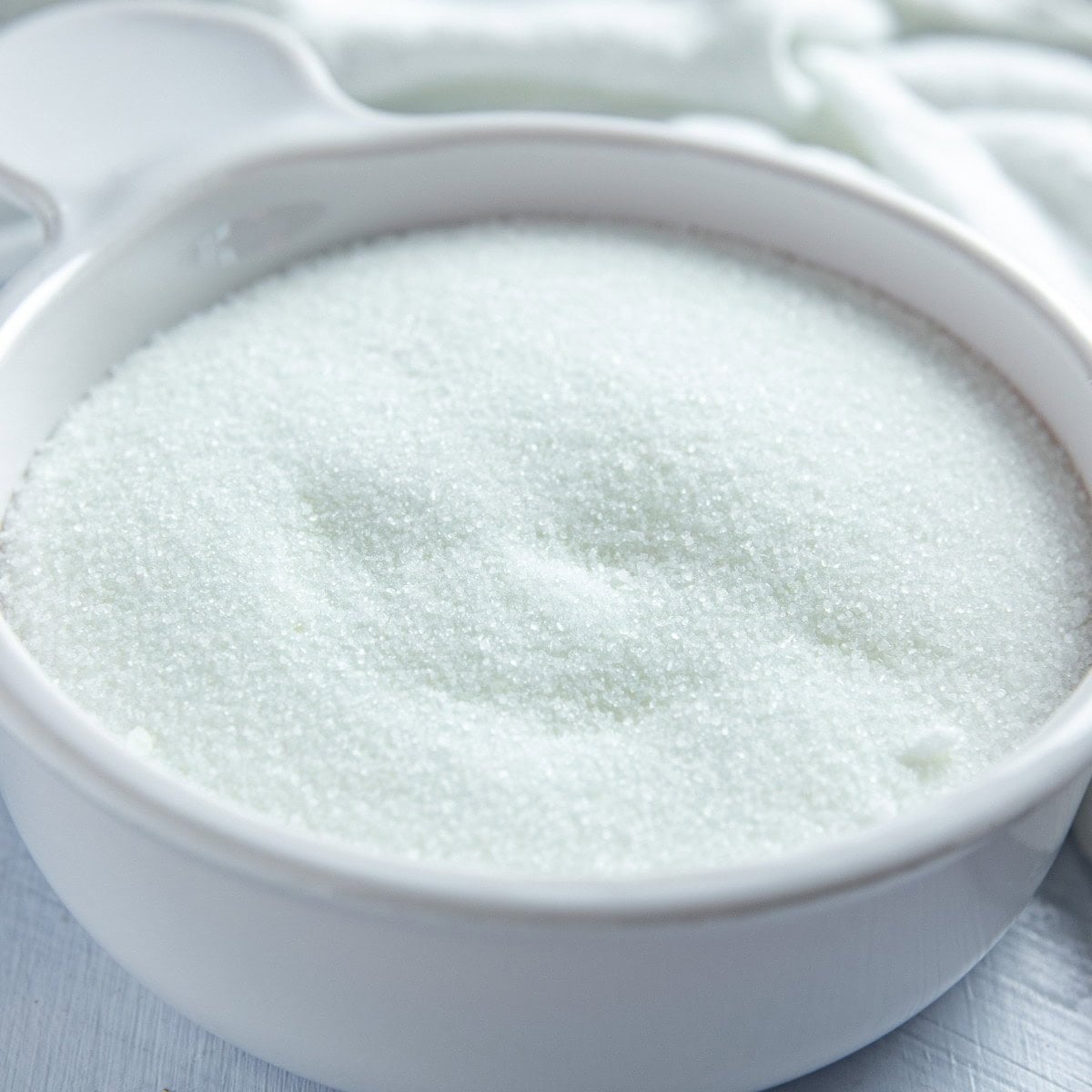 Granulated sugar in a white bowl.