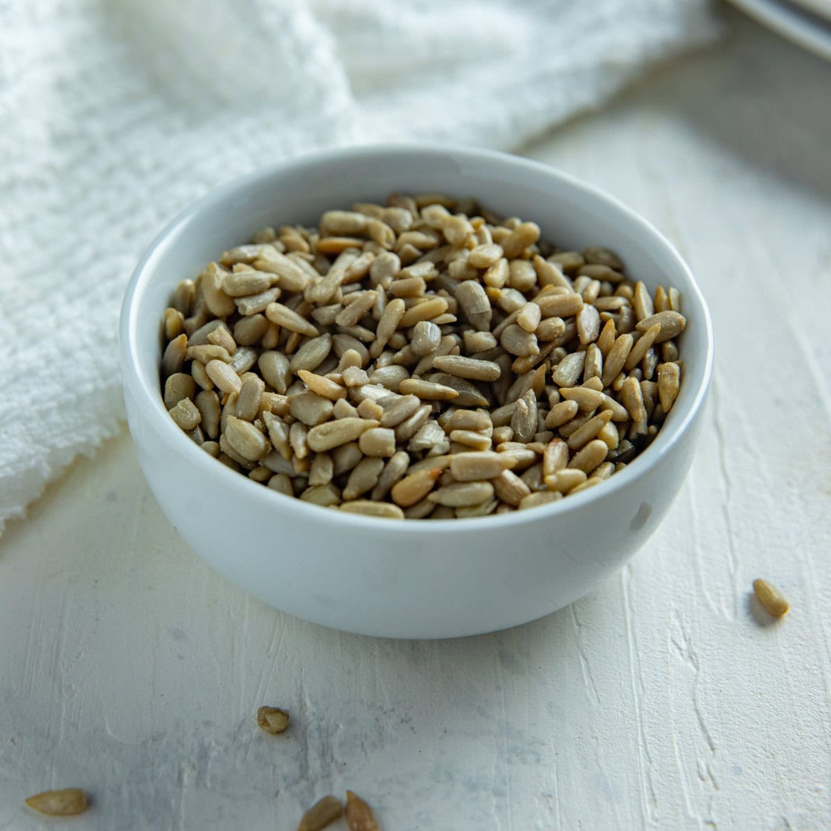 Whole sunflower seeds in a white bowl.