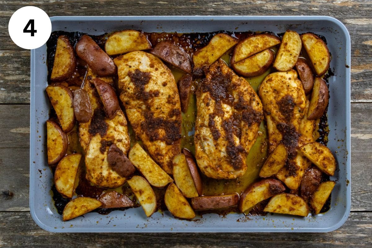 Baked chicken and potato wedges on a sheet pan.