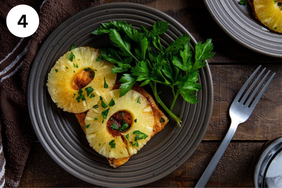 Overhead view of a plated baked salmon fillet with pineapple rings on top.