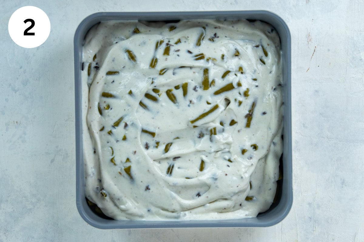 Layer of sour cream and cream of mushroom soup mixture spread on top of the green beans.