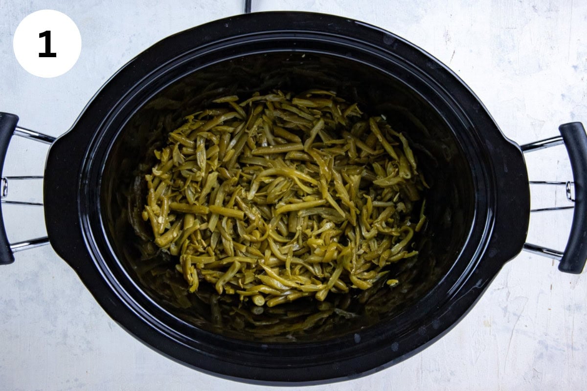 Drained green beans in the bottom of the crockpot.