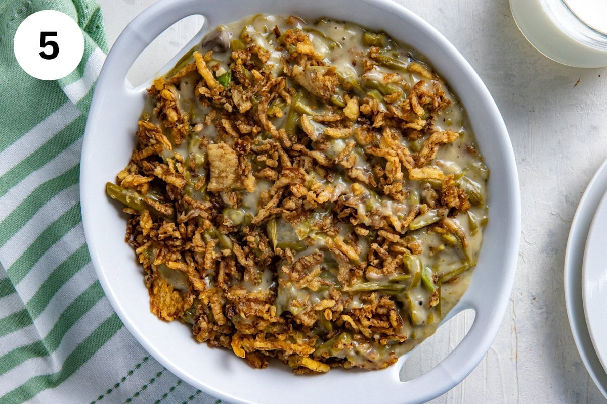 Cooked crockpot green bean casserole that's been transferred to a white serving bowl.