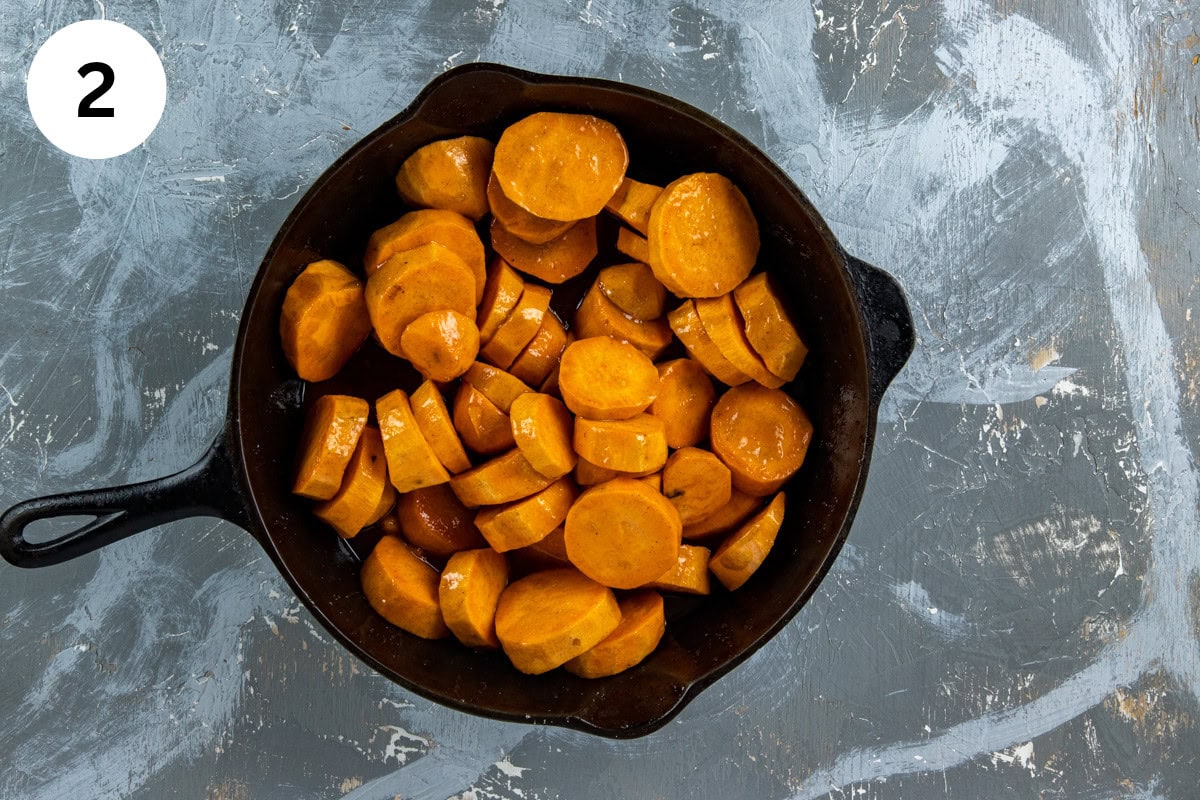 Sweet potato slices added to butter mixture in the cast iron skillet.